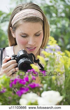 Stock Photograph - Young woman photographing flowers. Fotosearch