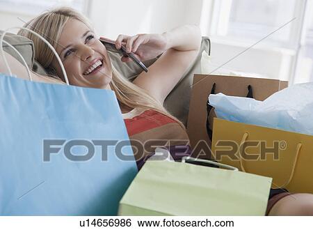 Young woman talking on mobile phone surrounded by shopping bags View Large Photo Image Stock Photograph - Young woman talking on mobile phone surrounded by shopping bags. Fotosearch