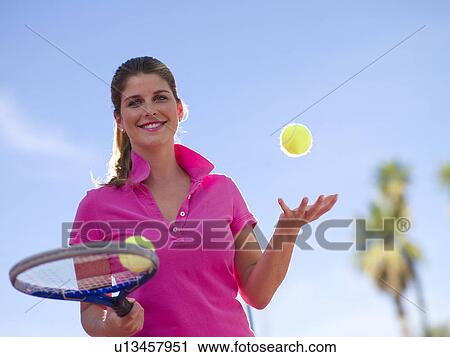 Stock Image - Young woman with tennis balls and racket. Fotosearch