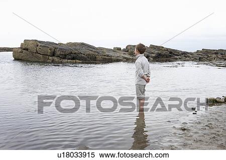 Stock Photography - Boy daydreaming on beach. Fotosearch