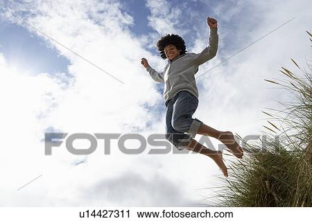 Stock Image - Boy jumping over dune. Fotosearch