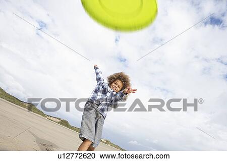 Stock Image - Boy playing frisbee on beach. Fotosearch
