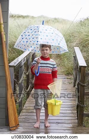 Picture - Boy standing on footbridge with umbrella. Fotosearch