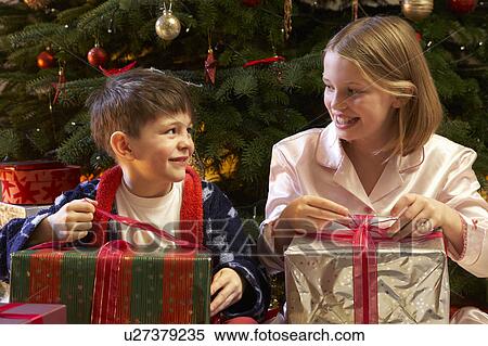 Children Opening Christmas Present In Front Of Tree View Large Photo Image Stock Photography - Children Opening Christmas Present In Front Of Tree. Fotosearch