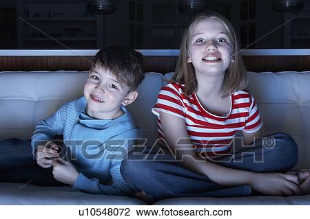 Stock Image - Children Watching TV Together Sitting On Sofa. Fotosearch