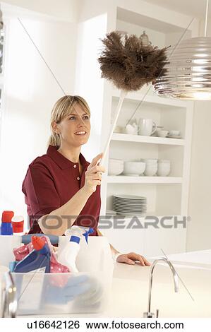 Stock Photograph - Cleaner Working In Domestic Kitchen With Feather Duster. Fotosearch