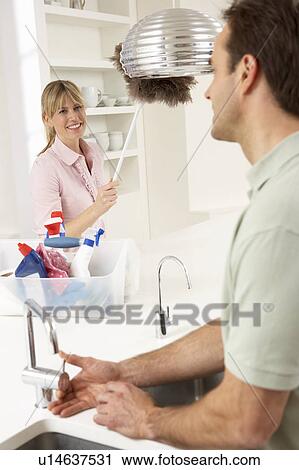 Stock Image - Couple Doing Housework In Kitchen Together. Fotosearch