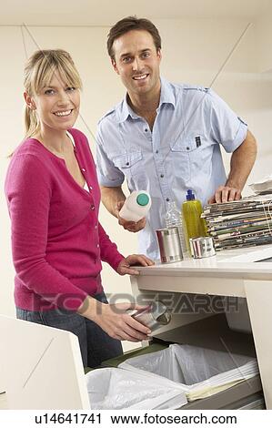Stock Image - Couple Recyling Waste At Home. Fotosearch