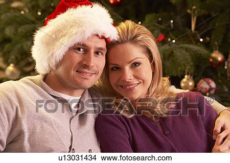 Picture - Couple Relaxing In Front Of Christmas Tree. Fotosearch
