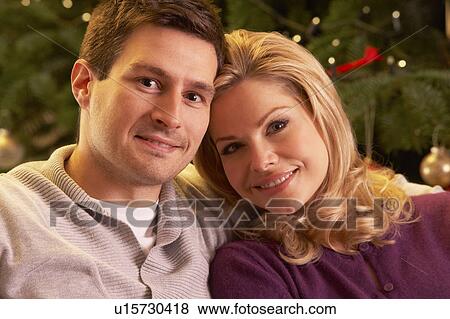 Stock Photo - Couple Relaxing In Front Of Christmas Tree. Fotosearch
