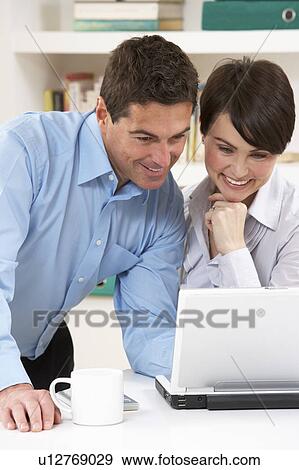 Stock Photo - Couple Working From Home Using Laptop. Fotosearch