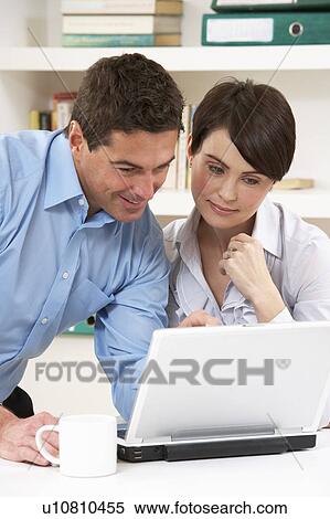 Stock Photography - Couple Working From Home Using Laptop. Fotosearch