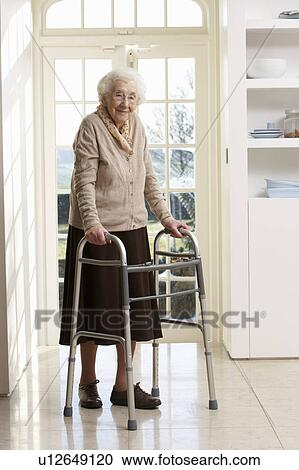 Stock Image - Elderly Senior Woman Using Walking Frame. Fotosearch