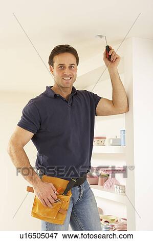 Stock Photo - Electrician Installing Light Fitting In Home. Fotosearch