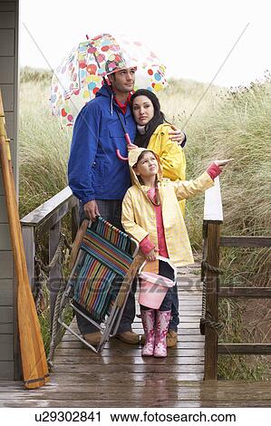 Stock Image - Family on beach with umbrella. Fotosearch