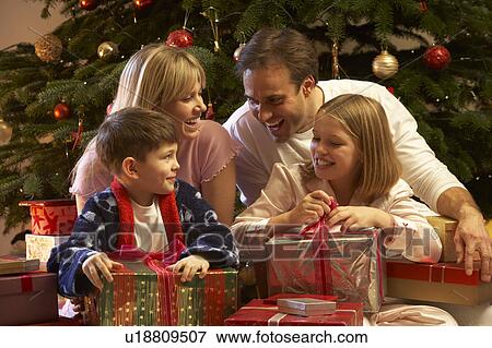 Family Opening Christmas Present In Front Of Tree View Large Photo Image Stock Photo - Family Opening Christmas Present In Front Of Tree. Fotosearch