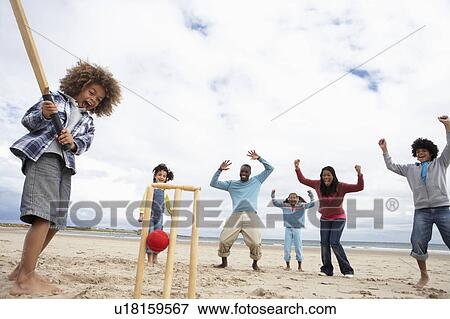 Stock Photo - Family playing cricket on beach. Fotosearch
