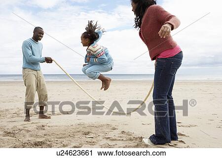 Stock Image - Family playing on beach. Fotosearch