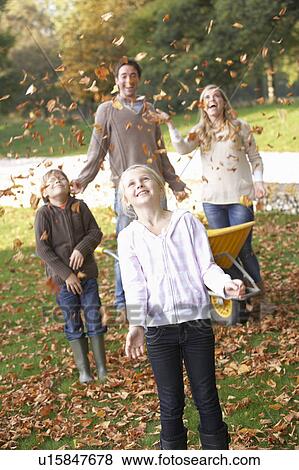 Family throwing autumn leaves into the air in garden View Large Photo Image Stock Photo - Family throwing autumn leaves into the air in garden. Fotosearch