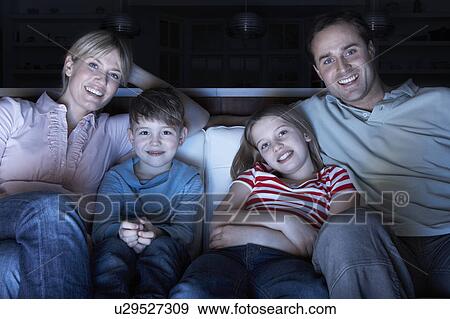 Stock Photo - Family Watching TV On Sofa Together. Fotosearch