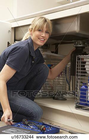Picture - Female Plumber Working On Sink In Kitchen. Fotosearch