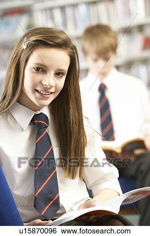 Stock Photograph - Female Teenage Student In Library Reading Book. Fotosearch