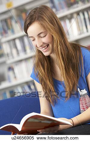 Stock Photography - Female Teenage Student In Library Reading Book. Fotosearch