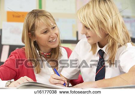 Stock Photo - Female Teenage Student Studying In Classroom With Teacher. Fotosearch