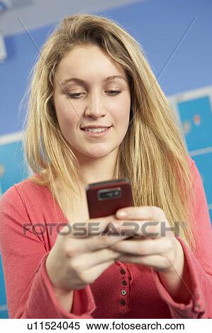 Stock Photography - Female Teenage Student Using Mobile Phone By Lockers In School. Fotosearch