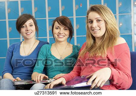 Stock Image - Female Teenage Students Relaxing By Lockers In School. Fotosearch