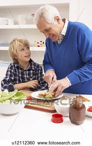 Stock Image - Grandfather And Grandson Making Sandwich In Kitchen. Fotosearch