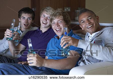 Stock Photography - Group Of Teenage Boys Sitting On Sofa At Home Watching Drinking. Fotosearch