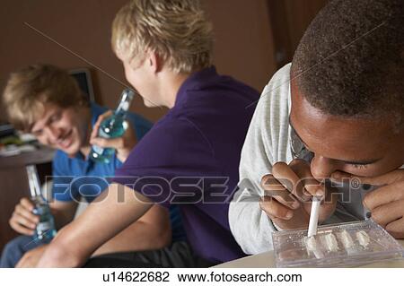 Stock Image - Group Of Teenage Boys Taking Drugs At Home. Fotosearch
