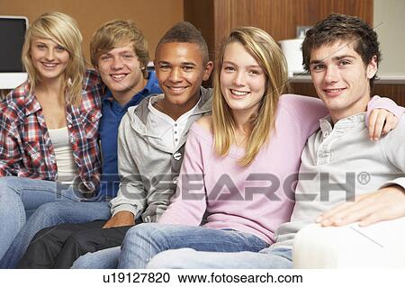 Stock Image - Group Of Teenage Friends Sitting On Sofa At Home. Fotosearch