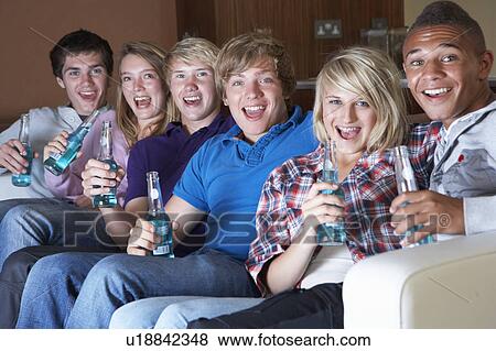 Group Of Teenage Friends Sitting On Sofa At Home Watching Drinki View Large Photo Image Stock Photo - Group Of Teenage Friends Sitting On Sofa At Home Watching Drinki. Fotosearch