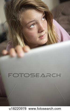 Stock Photo - Guilty Looking Teenage Girl Using Laptop At Home. Fotosearch