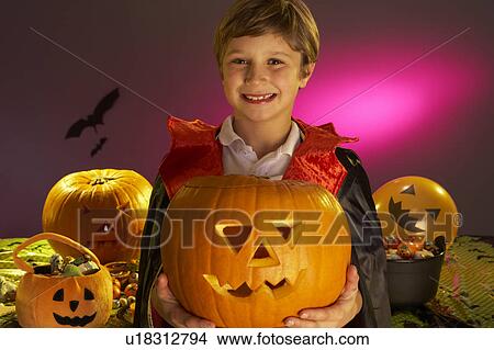 Halloween party with a boy child holding carved pumpkin View Large Photo Image Picture - Halloween party with a boy child holding carved pumpkin. Fotosearch
