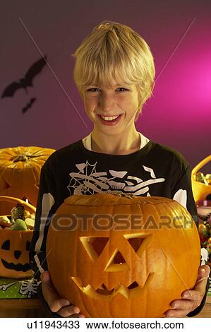 Halloween party with a boy holding carved pumpkin View Large Photo Image Stock Image - Halloween party with a boy holding carved pumpkin. Fotosearch