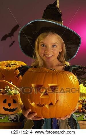 Picture - Halloween party with a child holding carved pumpkin. Fotosearch