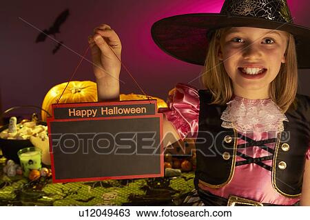 Stock Image - Halloween party with a child holding sign in hand. Fotosearch