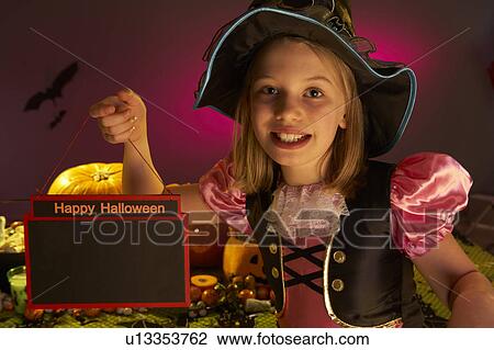 Stock Image - Halloween party with a child holding sign in hand. Fotosearch