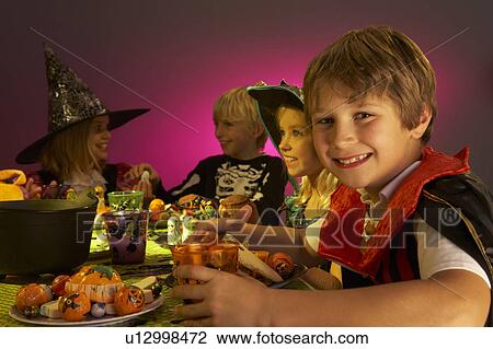 Stock Image - Halloween party with children having fun in fancy costumes. Fotosearch