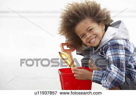 Happy boy at beach with bucket and spade View Large Photo Image Stock Photo - Happy boy at beach with bucket and spade. Fotosearch