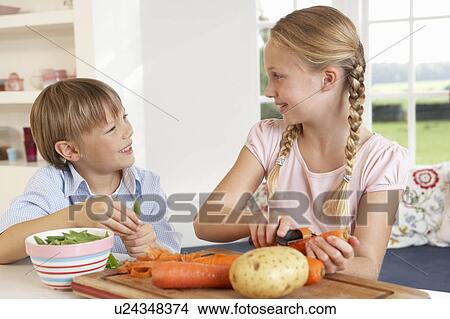 Picture - Happy children peeling vegetables in kitchen. Fotosearch