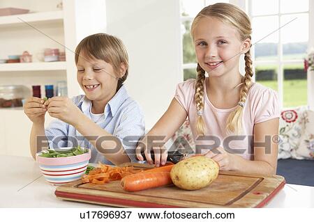 Happy children peeling vegetables in kitchen View Large Photo Image Stock Photo - Happy children peeling vegetables in kitchen. Fotosearch