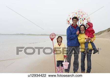 Stock Image - Happy family on beach with umbrella. Fotosearch