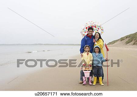 Stock Image - Happy family on beach with umbrella. Fotosearch