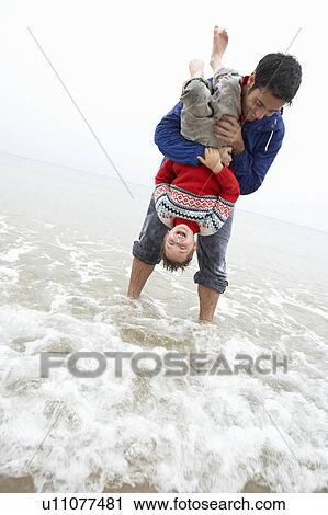 Stock Image - Happy father with son on beach. Fotosearch