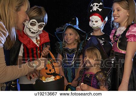 Stock Photo - Happy Halloween party with children trick or treating. Fotosearch