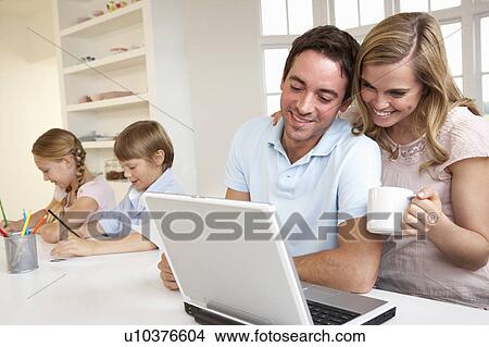 Picture - Happy young family looking and reading a laptop computer. Fotosearch